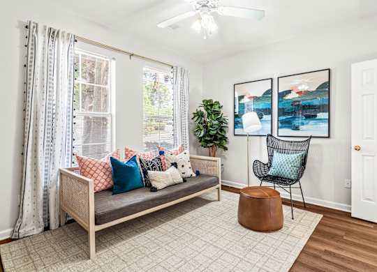 A living room with a couch, chair, and potted plant.