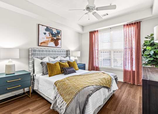 A bedroom with a bed, nightstand, and a ceiling fan.