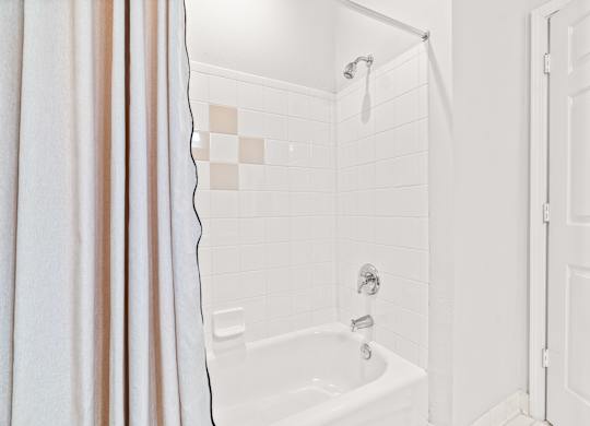 A white bathroom with a shower and a white door.