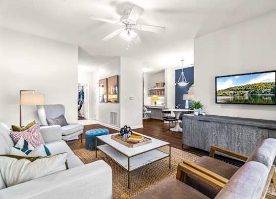 A living room with a white couch, a coffee table, and a television.