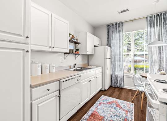 A kitchen with white cabinets and a rug on the floor.