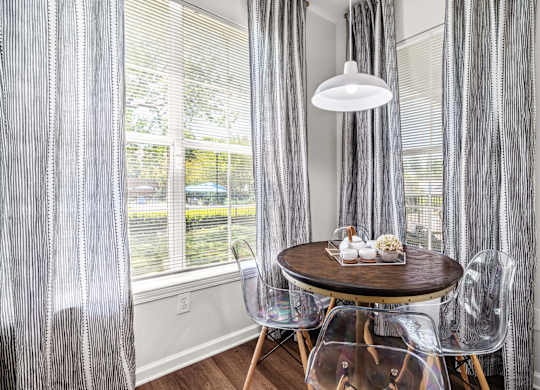 A dining room with a table set for two and a view of a backyard.