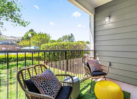 A balcony with a chair, a cushion and a pillow.