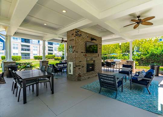 A patio with a table, chairs, and a fireplace.