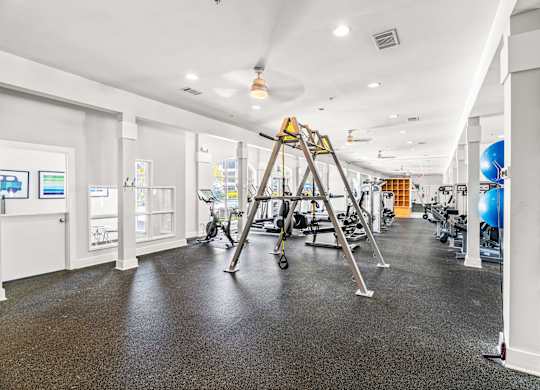 A gym with a variety of equipment including a treadmill, exercise balls, and weights.