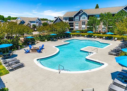 A large swimming pool surrounded by lounge chairs and umbrellas.