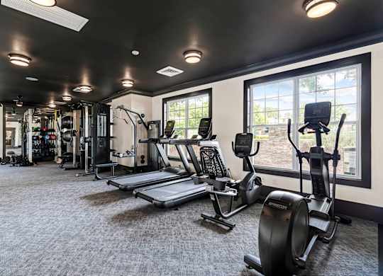 A gym with a variety of equipment including treadmills, weights, and exercise machines.