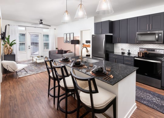 a kitchen and living room with black cabinets and a granite counter top