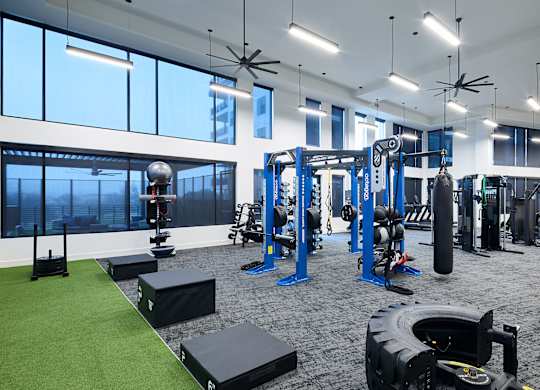 A gym with a variety of equipment including weights and a green artificial turf area.