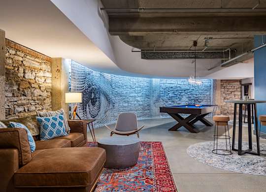 a living room with a pool table and a brick wall