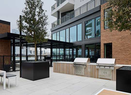 A modern outdoor seating area with a brick wall and a tree.