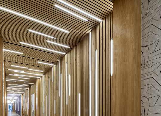 A long hallway with wood paneling and lighting on the ceiling.