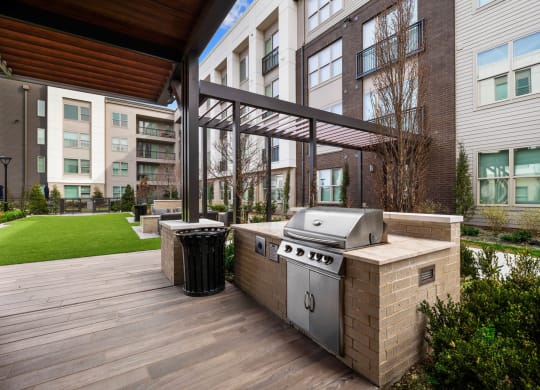 a barbecue grill on a deck in front of an apartment building