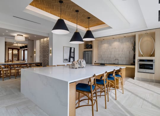 a large kitchen with a large white island and blue chairs