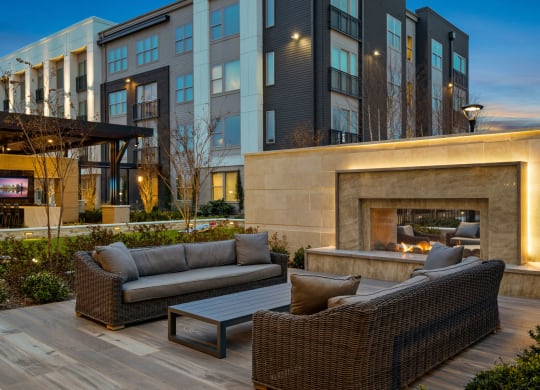a patio with couches and a fireplace in front of a building