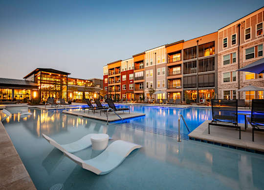 a swimming pool with lounge chairs and a coffee cup in front of a building