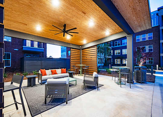 a patio with a couch chairs and tables and a pool in the background
