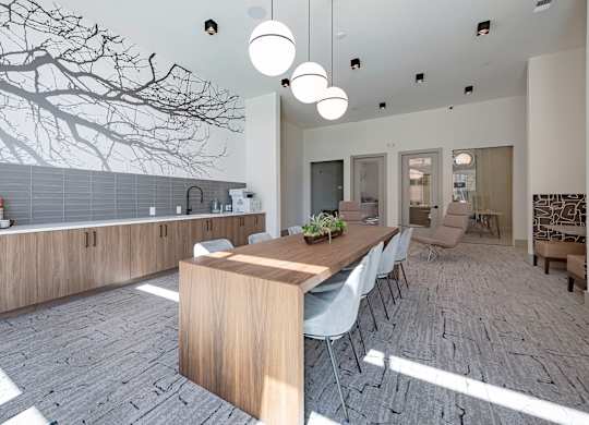 a long wooden table with white chairs in a room with a tree mural on the wall