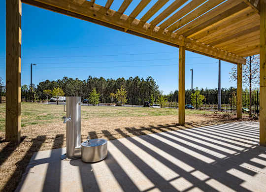a wooden pergola with a stainless steel water fountain in the middle