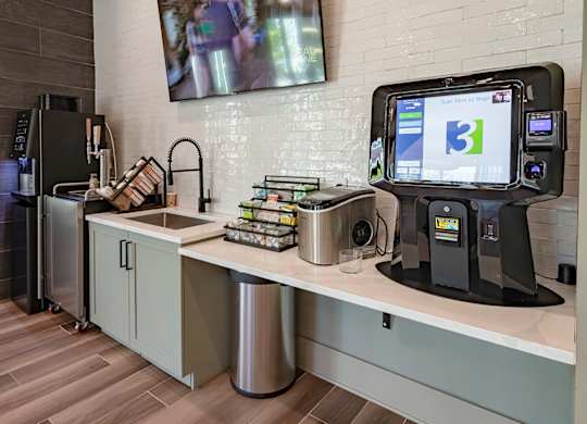 a coffee shop with a large tv on the wall and a kitchenette with a sink and