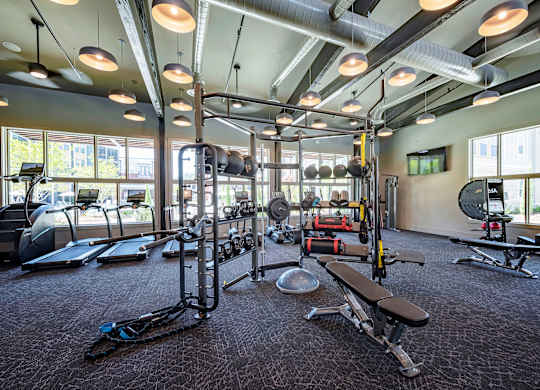 a spacious fitness center with cardio equipment and windows