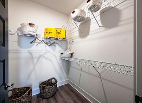 a walk in closet with white walls and a yellow box on a wire shelf