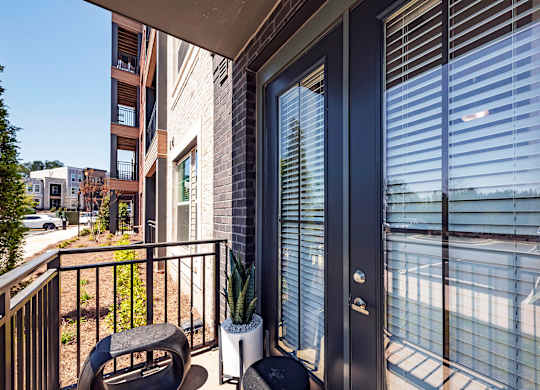 a balcony with a chair and a table with a potted plant on it