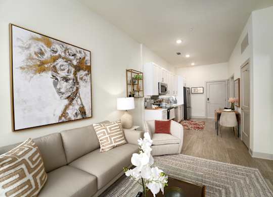 A living room with a large painting on the wall and a beige couch.