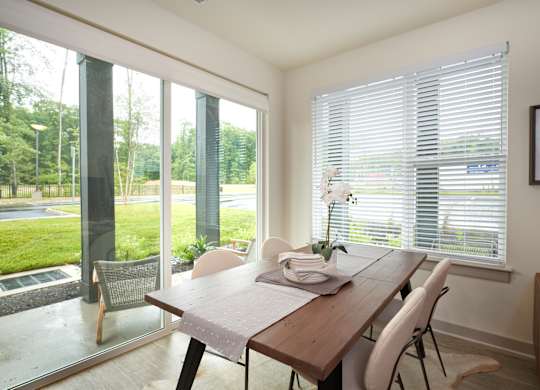 A dining room with a table and chairs and a view of the outside.