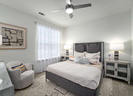 A bedroom with a large bed, a chair, and a ceiling fan.