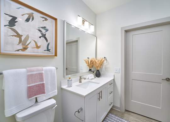 A white bathroom with a towel hanging on the toilet.