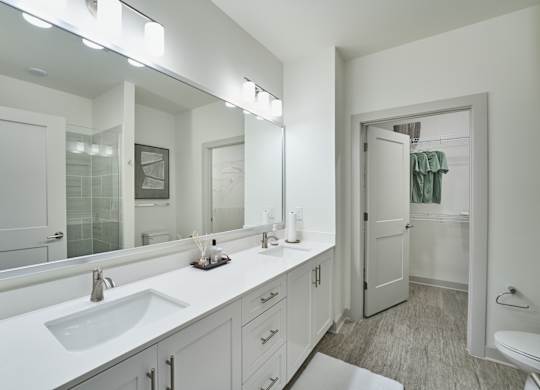 A white bathroom with a sink, mirror, and toilet.
