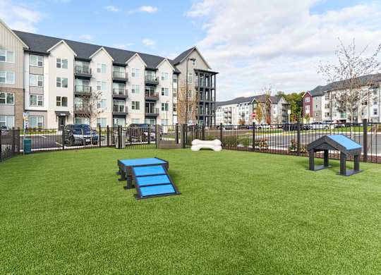A park area with a blue slide in front of apartment buildings.