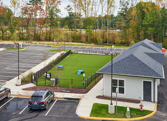 A parking lot with a small building and a green field.