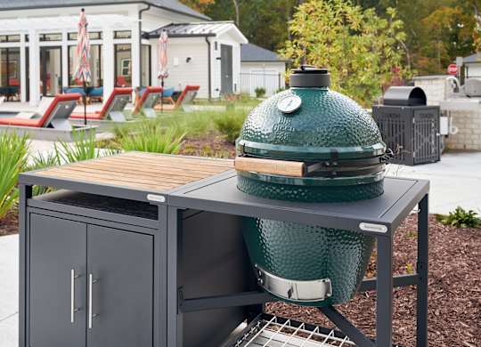 A green grill is on a table outside.