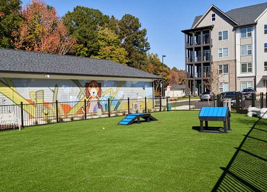 A park with a mural on a wall and a blue bench.