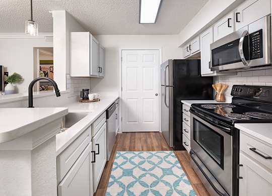 A kitchen with black appliances and white cabinets.