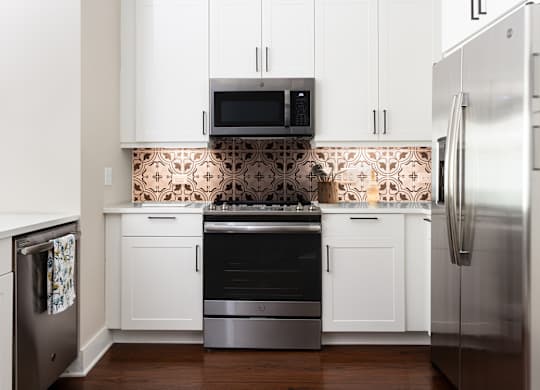 a white kitchen with stainless steel appliances and white cabinets