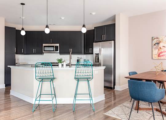 an open kitchen and dining area with bar stools in front of a kitchen island
