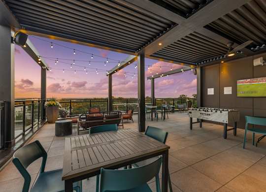 A patio with a table and chairs overlooking a sunset.