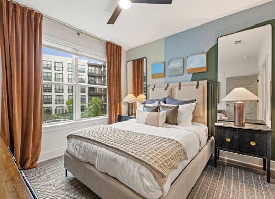 A bedroom with a large bed and a view of a building outside the window.