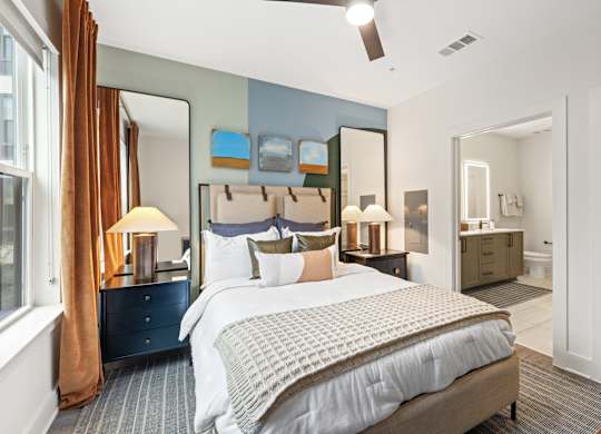 A bedroom with a large bed and a dresser with a mirror above it.