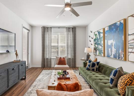 A living room with a green couch and a wooden floor.