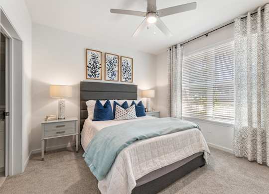 A bedroom with a bed, nightstand, and a ceiling fan.