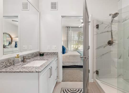 A bathroom with a marble countertop and a walk-in shower.
