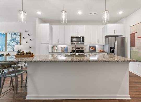 A kitchen with a granite countertop and stainless steel appliances.