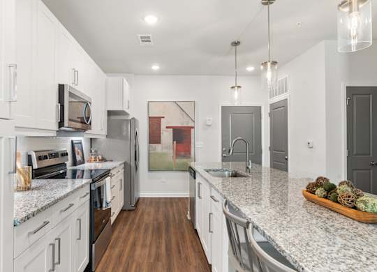 A kitchen with white cabinets and a marble countertop.