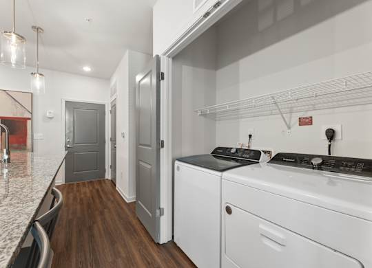 A modern kitchen with white appliances and a marble countertop.