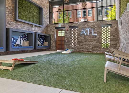 A backyard with a lawn, a bench, and a cornhole game set up.
