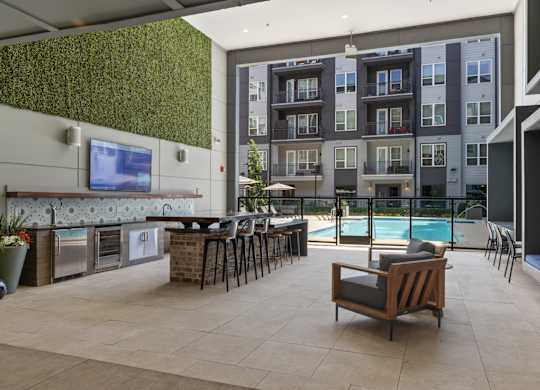 A modern outdoor kitchen area with a bar and chairs.